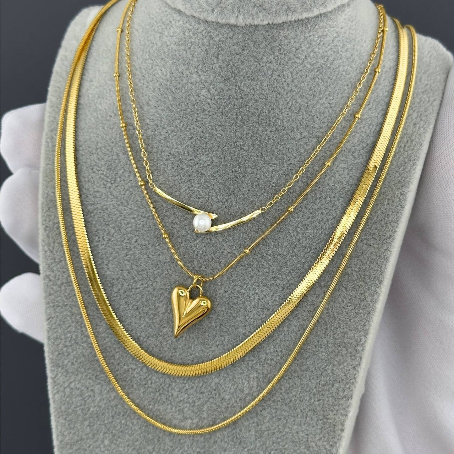 Gold necklaces with heart pendant on a gray stand