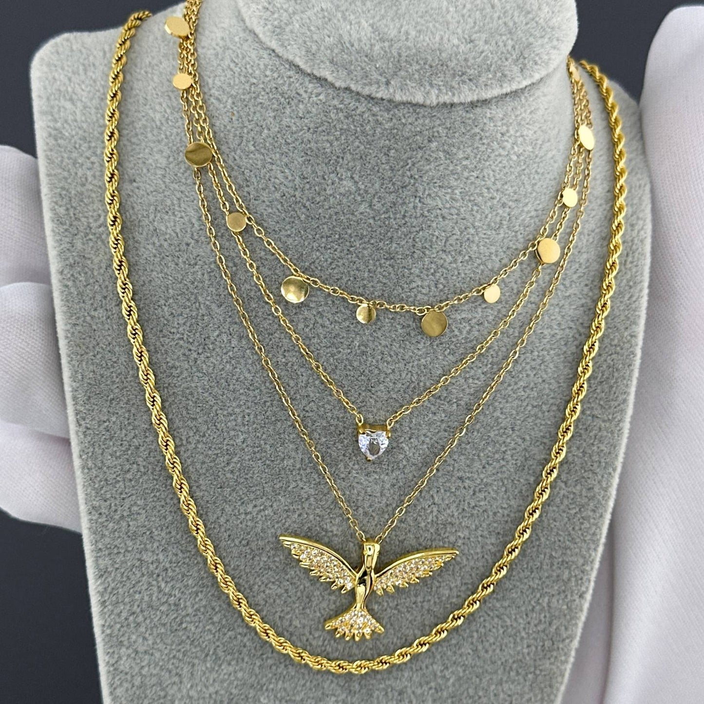 Gold necklaces with a small heart pendant with cubic zirconia on a grey stand