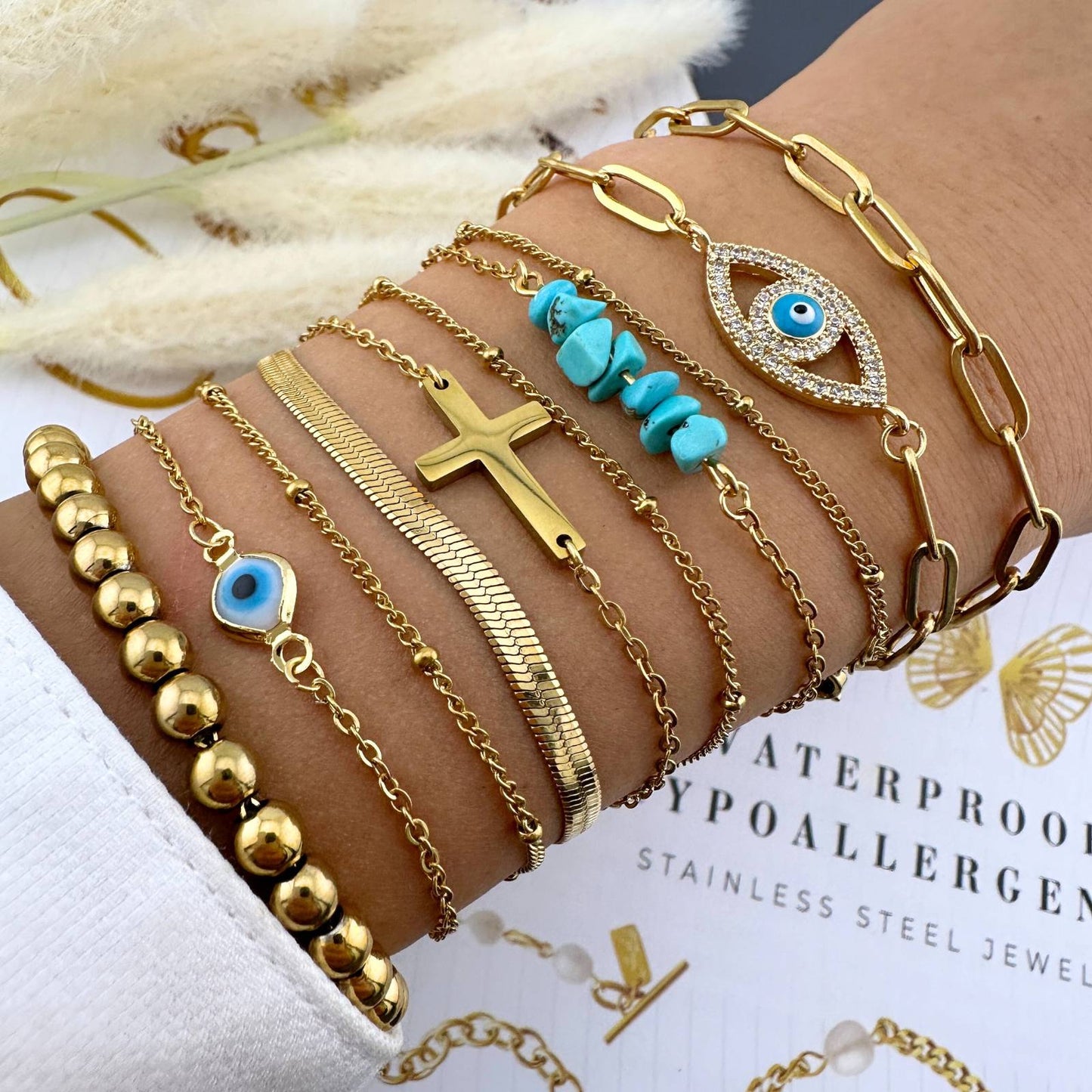 Multiple gold bracelets with various designs on a wrist, with a blurred background.