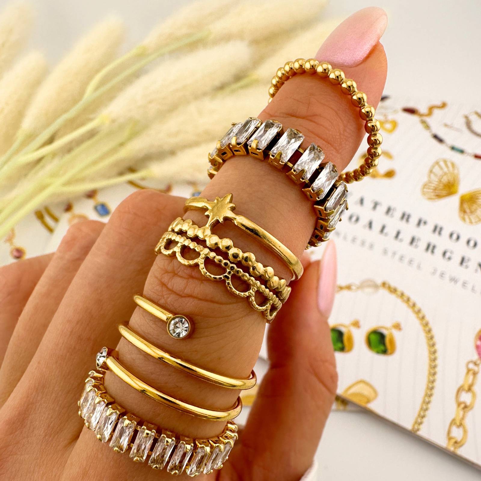 Hand wearing multiple gold rings with a blurred background