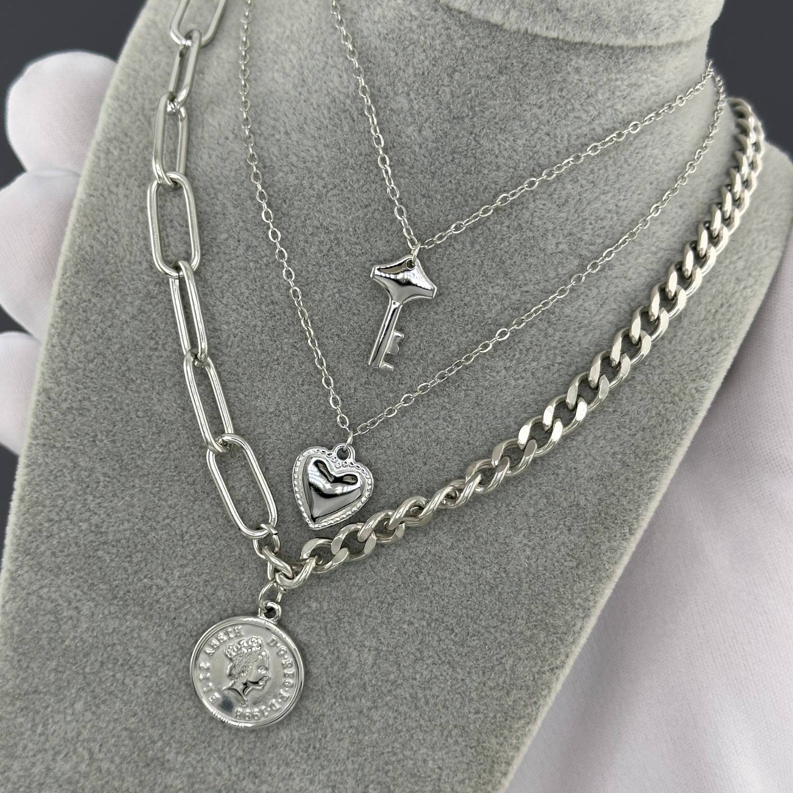 Stack of silver necklaces on a gray stand