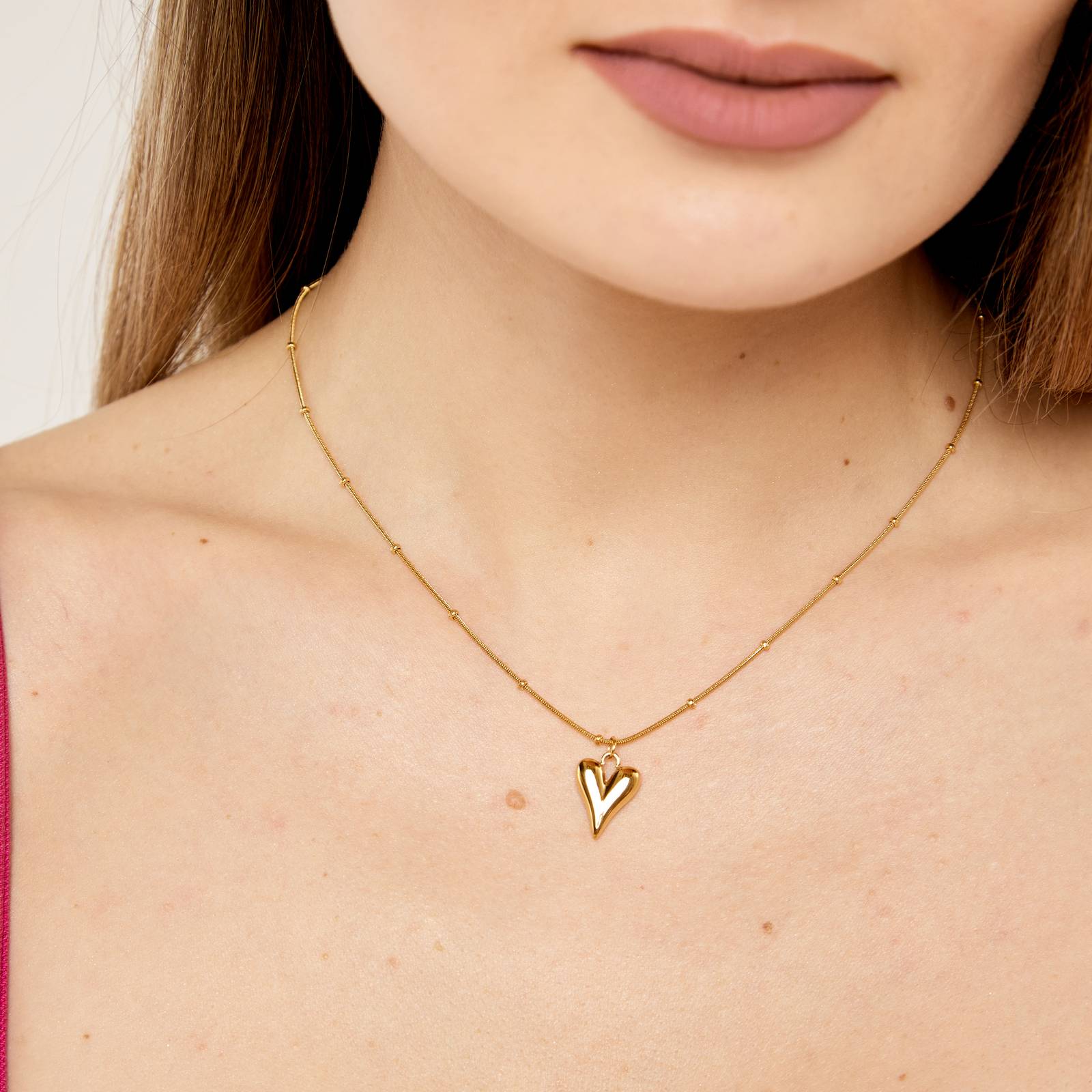 Gold necklace with a heart pendant worn by a person