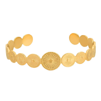 Gold bracelet with circular and floral patterns on a white background