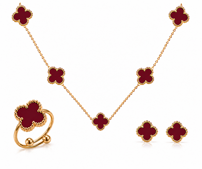 Gold jewelry set with red clover-shaped stones on a white background