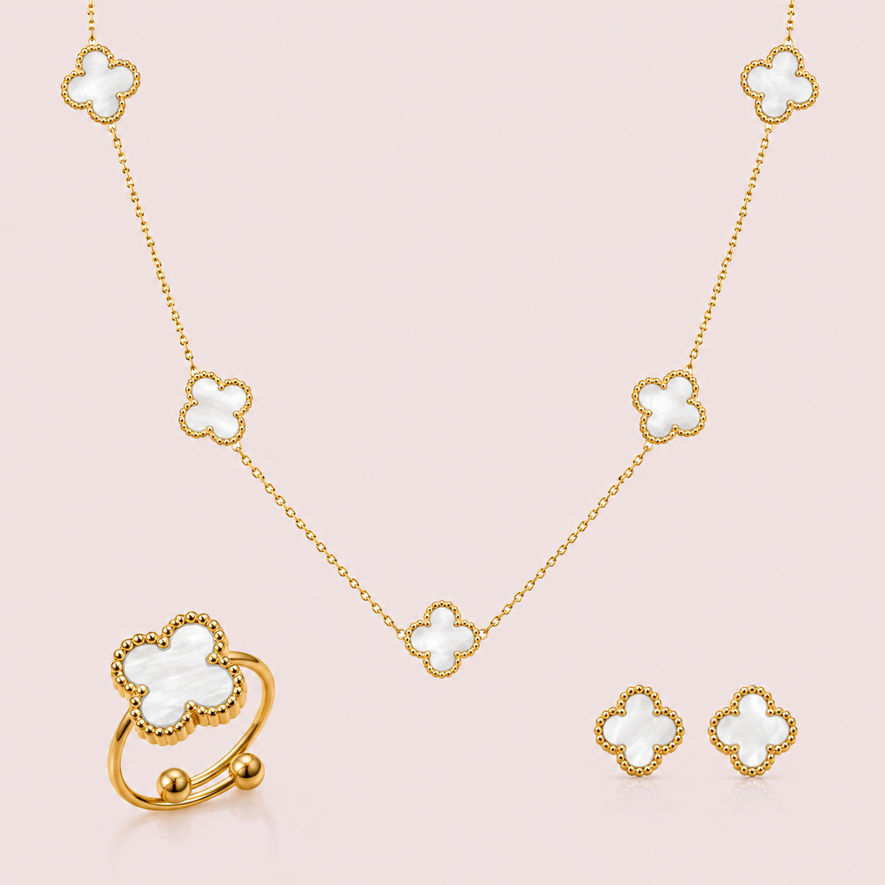 Gold jewellery set with clover-shaped pendants on a pink background